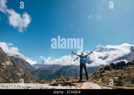 Junger Wanderer Backpacker Mann aufsteigende Arme mit Trekking-Stöcke genießen den Thamserku 6608m Berg während der Höhenakklimatisation Wanderung. Everest Ba Stockfoto
