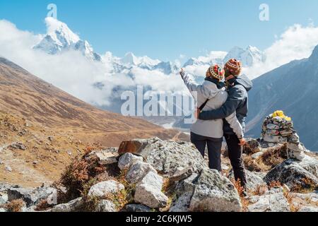 Paar auf der Everest Base Camp Trekkingroute bei Dughla 4620m. Backpacker links Rucksäcke, umarmen und genießen Sie Talblick mit Ama Da Stockfoto