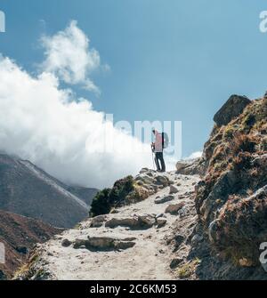 Wanderer Mann Silhouette auf Wolken Hintergrund stehend auf Pfad über das Imja Khola Tal und genießen Sie die Aussicht auf die Berge während eines Everest Base Camp tr Stockfoto