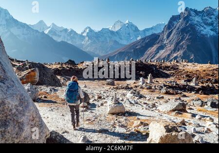 Junge Backpacker-Frau auf der Everest Base Camp Trekkingroute mit Trekkingstöcken und Blick auf das Tal mit Ama Dablam Gipfel. Sie kam zu Eva Stockfoto