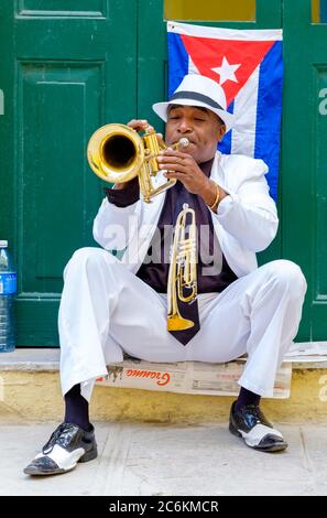 Kubanischer Musiker, der neben einer kubanischen Flagge in Havanna Trompete spielt Stockfoto