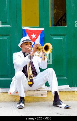 Kubanischer Musiker, der neben einer kubanischen Flagge in Havanna Trompete spielt Stockfoto