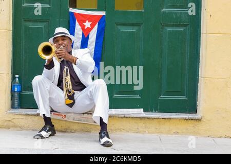 Kubanischer Musiker, der neben einer kubanischen Flagge in Havanna Trompete spielt Stockfoto