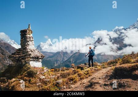 Junger Wanderer Backpacker Mann mit Trekkingstöcken genießen den Ama Dablam 6814m Gipfel Berg während Akklimatisation Wanderung in der Nähe von buddhistischen Stupa.Everest Bas Stockfoto