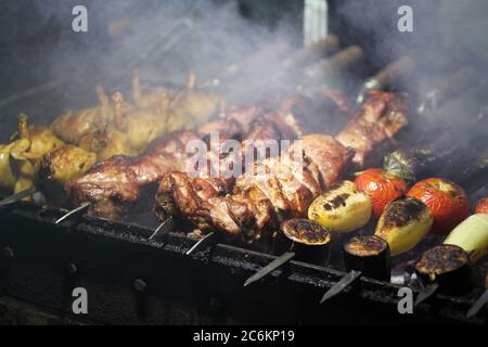 Grill mit Schweinefleisch, Wachtel und Gemüse auf Spieße Braten auf einem Grillbräter. Nahaufnahme Stockfoto