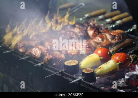 Grill mit Schweinefleisch, Wachtel und Gemüse auf Spieße Braten auf einem Grillbräter. Nahaufnahme Stockfoto