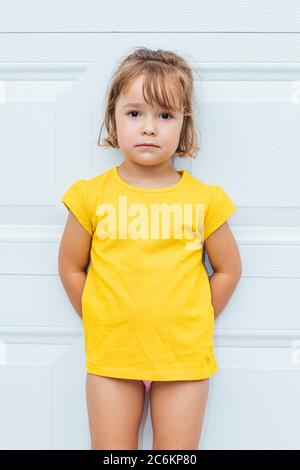 Liebenswert blonde-haarige Mädchen trägt ein gelbes Hemd lehnt sich vor weißem Hintergrund Stockfoto