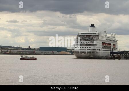 Ein Fährschiff von Tilbury nach Gravesend fährt am Columbus-Schiff vorbei, das seit April im Hafen von Tilbury an der Themse angedockt ist, als alle seine Operationen wegen der Pandemie-Sperre von Covid 19 in Großbritannien ausgesetzt wurden.40,000 Kreuzfahrtjobs könnten durch die Sperrung verloren gehen Das Foreign & Commonwealth Office (FCO) gibt allen Touristen den Rat, dass sie bis zum Oktober keine Ferien auf See verbringen sollten. Dies basiert auf medizinischen Gutachten für die Coronavirus-Präventionsmaßnahmen von Public Health England. Stockfoto