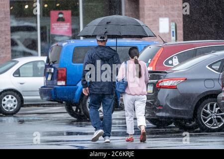 Ein paar Spaziergänge im Supermarkt Parkplatz im Regen. Stockfoto