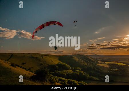 Devils Dyke, Brighton, Sussex, Großbritannien. Juli 2020. Ein sehr angenehmer Abend in den schönen South Downs nördlich von Brighton. Gleitschirmflieger fliegen auf dem NNW Wind, wenn die Sonne untergeht. Kredit: David Burr/Alamy Live Nachrichten Stockfoto