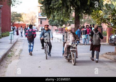 Neu Delhi / Indien - 16. Februar 2020: Zwei alte Männer reiten Motorrad und Sicherheitsmann Fahrrad fahren innerhalb der Universität Campus Stockfoto