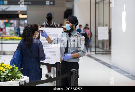 Toronto, Kanada. Juli 2020. Ein Sicherheitsbeauftragter mit Gesichtsmaske überprüft am 10. Juli 2020 die Temperatur eines Kunden außerhalb eines Apple-Stores im CF Toronto Eaton Centre in Toronto, Kanada. Die Wirtschaft fügte 953,000 Arbeitsplätze in Kanada, und die Arbeitslosenquote sank auf 12.3 Prozent im Juni, als Unternehmen wieder nach der Schließung COVID-19, nach Statistik Kanada Freitag. Quelle: Zou Zheng/Xinhua/Alamy Live News Stockfoto