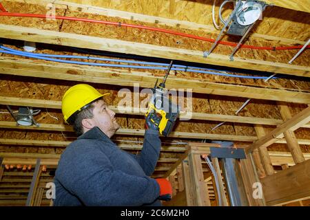 Zimmermann in der Arbeit bohrt Löcher für elektrische Drähte mit Holzdecke Stockfoto