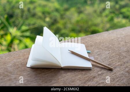 Kleines weißes Notizbuch auf Tisch mit Blick auf die Berge im Hintergrund. Stockfoto