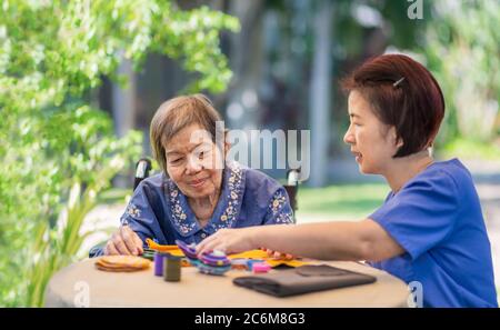 Ältere Frau mit Betreuer in der Nadel Handwerk Ergotherapie für Alzheimer oder Demenz Stockfoto