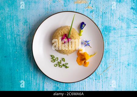 Quinoa-Teller-Präsentation mit essbaren Blumen dekoriert Stockfoto