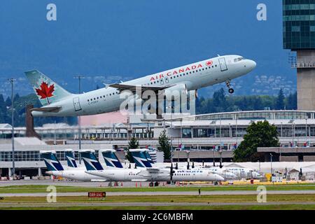 Richmond, British Columbia, Kanada. Juli 2020. Ein Airbus A320 (C-FGKH) von Air Canada hebt am 7. Juli 2020 vom internationalen Flughafen Vancouver ab und fliegt nach Ottawa. Im Hintergrund bleiben die WestJet Encore Bombardier Q400-Flugzeuge wegen der COVID-19-Pandemie wegen der geringeren Flugreisen geparkt. Kredit: Bayne Stanley/ZUMA Wire/Alamy Live Nachrichten Stockfoto