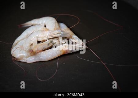 Garnelen auf schwarzem Teller mit Wassertropfen Stockfoto