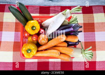 Korb mit frischem Gemüse Karotten, Rettich, Paprika, Tomaten, Brinjal, Gurke auf dem Tisch Stockfoto