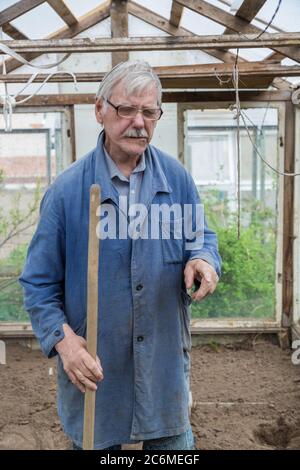 Fröhlicher älterer Mann, der Garten im Frühling grub Stockfoto