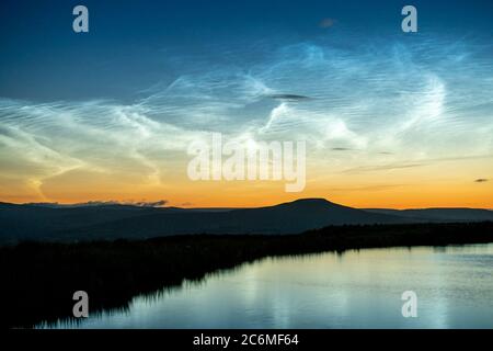 Der Komet Neowise C/2020 F3 leuchtet im Nachthimmel hell durch nächtliche Wolken, wenn er über die Brecon Beacons in South Wales, Großbritannien, Stockfoto