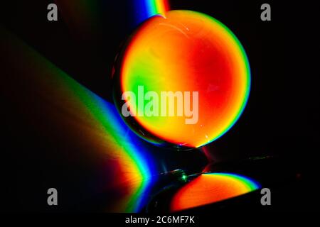 Farben des Regenbogenprodukts des gebrochenen Lichts, das das Spektrum des Lichts zeigt, das von einem sphärischen Glasobjekt Physik und Optik gebogen wird Stockfoto