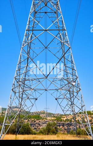 Die Hochspannungsleitung liegt auf einem felsigen Gelände. Stockfoto