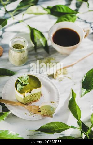 Grüner Matcha Käsekuchen und schwarzer Kaffee in der Tasse, selektiver Fokus Stockfoto