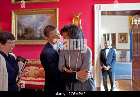 Präsident Barack Obama umarmt der First Lady Michelle Obama im Roten Zimmer während Senior Advisor Valerie Jarrett Lächeln vor der nationalen Zeitung Publishers Association (NNPA) Rezeption 3/20/09. Stockfoto