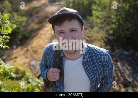 Junger Kaukasianer, schöner Mann, lächelnd, beim Wandern im Wald Stockfoto