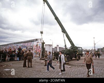 Ost-berliner überqueren auf den Westen als ein Kran ist die Berliner Mauer am Potsdamer Platz zu demontieren. Stockfoto