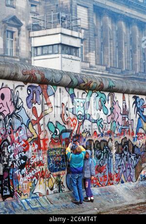 Westdeutsche Kinder versuchen, Chip, ein Stück der Berliner Mauer als Souvenir. Ein Teil der Mauer wurde bereits am Potsdamer Platz abgerissen. Stockfoto