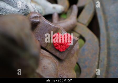 Verträumte Engelstatue mit gehäkeltem roten Herzen. Stockfoto