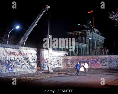 Die Anwohner freuen sich als Kran einen Abschnitt der Berliner Mauer neben dem Brandenburger Tor entfernt. Stockfoto