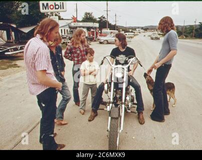 Mann auf Harley Davidson Motorrad stoppt mit Freunden zu sprechen, die Anfang der 1970er Jahre (kleine Stadt in Texas) Stockfoto