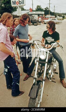 Mann auf Harley Davidson Motorrad hält mit Ihren Freunden und die Zigarette 1970Beleuchtung s Gespräch Stockfoto