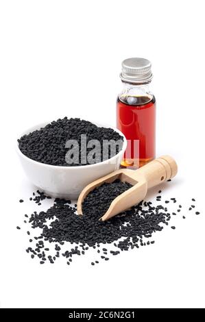 Schwarze Kümmel in Schüssel und ätherisches Öl in Glasflasche. Nigella sativa isoliert auf weißem Hintergrund. Stockfoto