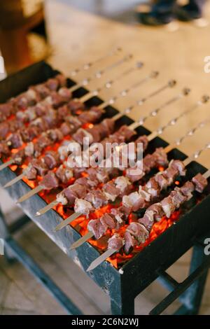 Grill auf dem Grill. Shashlik aus Fleischwürfeln auf den Spießen während des Kochens auf dem mangal über Holzkohle im Freien Stockfoto