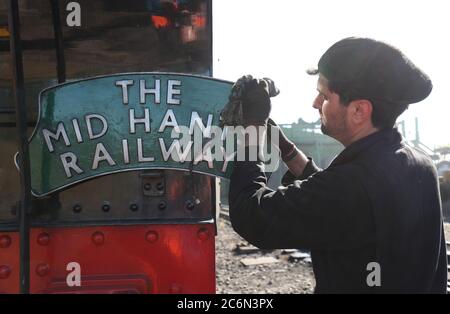 Ein Schild für die Mid Hants Railway wird auf der Rückseite der British Railways Ivatt Class 2MT Tank Engine 41312 am Bahnhof von Ropley gereinigt, da die Mid Hants Railway, auch bekannt als Watercress Line, sich nach der Lockerung der Sperrbeschränkungen in England darauf vorbereitet, der Öffentlichkeit wieder zu öffnen. Stockfoto