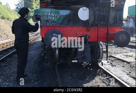 Ein Schild für die Mid Hants Railway wird auf der Rückseite der British Railways Ivatt Class 2MT Tank Engine 41312 am Bahnhof von Ropley gereinigt, da die Mid Hants Railway, auch bekannt als Watercress Line, sich nach der Lockerung der Sperrbeschränkungen in England darauf vorbereitet, der Öffentlichkeit wieder zu öffnen. Stockfoto