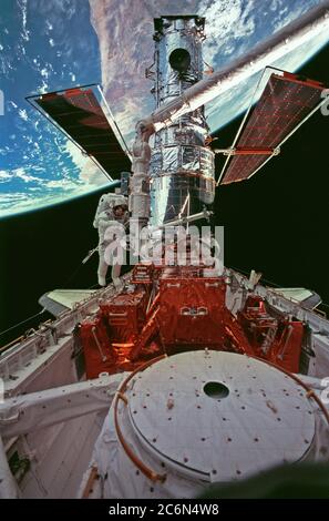 (15. Februar 1997) --- Diese breite Aufnahme des Hubble Space Telescope (HST) in Discovery's Cargo Bay, wurde gegen Australien zurückfallen gelassen, während der dritten STS-82 Spacewalk aufgenommen, um das Observatorium in der Umlaufbahn zu instand zu setzen. Astronaut Steven L. Smith (links von der Mitte) arbeitet in der Nähe der Fußstütze des Remote Manipulator Systems (RMS). Astronaut Mark C. Lee, Nutzlastkommandant, der mit Smith die Aufgaben des Weltraumspaziergangs teilte, war aus dem Rahmen. Stockfoto