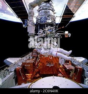 (11-21. Februar 1997) --- Astronaut Gregory J. Harbaugh, Missionsspezialist, schwimmt horizontal in der Frachtbucht des erdumkreisenden Space Shuttle Discovery, nach dem Rückfallenlassen gegen seinen riesigen temporären Passagier, das Hubble Space Telescope (HST). Harbaugh, der diese Spacer-Aktivität mit Astronaut Joseph R. Tanner (aus dem Rahmen) teilt, ist tatsächlich an seinem Helmvisier im 70mm-Rahmen erkennbar. Er befindet sich in der Nähe des zweiten Axialträgers (SAC), des Axial Scientific Instrument Protection Enclosure (ASIPE). STS-82 markiert den ersten Flug der Austrittsschleuse, teilweise sichtbar am unteren Bildrand. Stockfoto