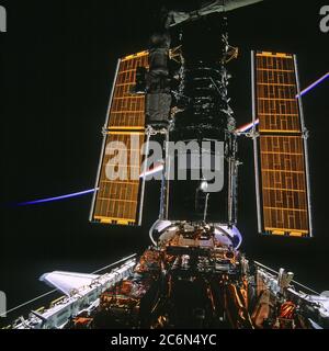 (11-21. Februar 1997) --- Diese Ansicht des Hubble Space Telescope (HST), das vorübergehend im Frachtraum des Space Shuttle Discovery aufgenommen wurde, wurde bei Sonnenuntergang mit einer 70mm-Kamera aufgenommen, was dem Erdteil einen Regenbogeneffekt gab. Die Crew, die zwei Teams von zwei Astronauten an wechselnden Tagen für die Arbeit auf der HST verwendete, führte fünf Tage lang Extravehicular Activity (EVA) durch. Stockfoto