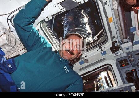 (19-27. Dezember 1999) --- Astronaut Curtis L. Brown, Missionskommandant, auf Discovery's Flugdeck. Das eingefangene Hubble Space Telescope (HST) ist durch die Fenster nur wenige Meter entfernt im Frachtraum des Shuttles sichtbar. Stockfoto