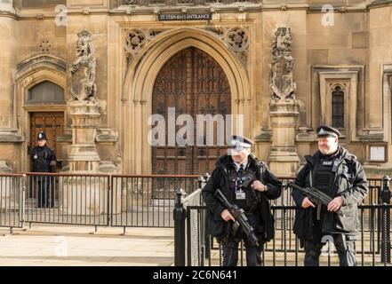 Die bewaffnete Polizei des diplomatischen Schutzes steht vor St. Stephen's Eingang zu den Houses of Parliament, Westminster, London, England, Großbritannien Stockfoto