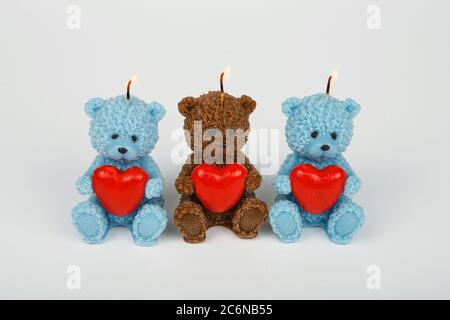 Lustige Souvenir Geschenkkerzen in Form von Teddybär mit rotem Herz. Eine brennende Kerze auf weiß. Kerzenschein. Valentinstag. Stockfoto