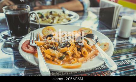 Ein Gericht aus einer Pasta mit Meeresfrüchten und Gemüse in einer roten Sauce. Nahaufnahme. Stockfoto