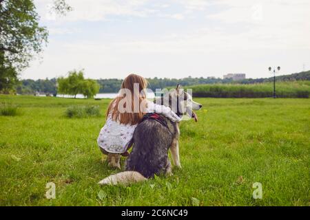 Kleines Mädchen umarmt Husky Hund während im flüchtigen sitzen und genießen schöne Aussicht. Freundschaft zwischen Haustier und Besitzer Stockfoto