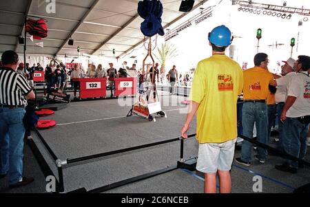 Bei den Finalspielen des Südost Regional Robotic Competition im KSC Visitor Complex 1999 beobachten Schiedsrichter in entgegengesetzten Ecken und Studententeams, wie zwei Roboter ihre Kissenscheiben auf eine Höhe von acht Fuß anheben, eines der Ziele des Wettbewerbs. Dreißig Schulen aus dem ganzen Land haben sich bei KSC für die Veranstaltung, die Gladiatorroboter gegeneinander in einem athletischen Wettbewerb stellt zusammengetakst. Die Roboter müssen die Kissenscheiben vom Boden holen, auf eine Plattform (mit Fahnen) klettern und den Kissenzwischenspeicher anheben, der von Schülerteams hinter der Schutzwand manövriert wird Stockfoto