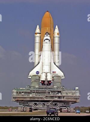 Auf der mobilen Trägerplattform und dem Crawler-Transporter thront Space Shuttle Discovery, der auf seinem Weg vom Vehicle Assembly Building zum Launch Pad 39B eine Wende im Crawlerway aushandelt. Während der Zeit auf dem Pad werden Orbiter, externer Tank und solide Raketenverstärker den letzten Vorbereitungen für den STS-103 Start unterzogen, der für den 6. Dezember 1999 um 2:37 Uhr EST geplant ist. Stockfoto